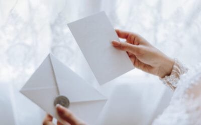 The bride in her hands holds a white envelope, an invitation, a gift sheet of paper. Close-up wedding photography, copy space, portrait.