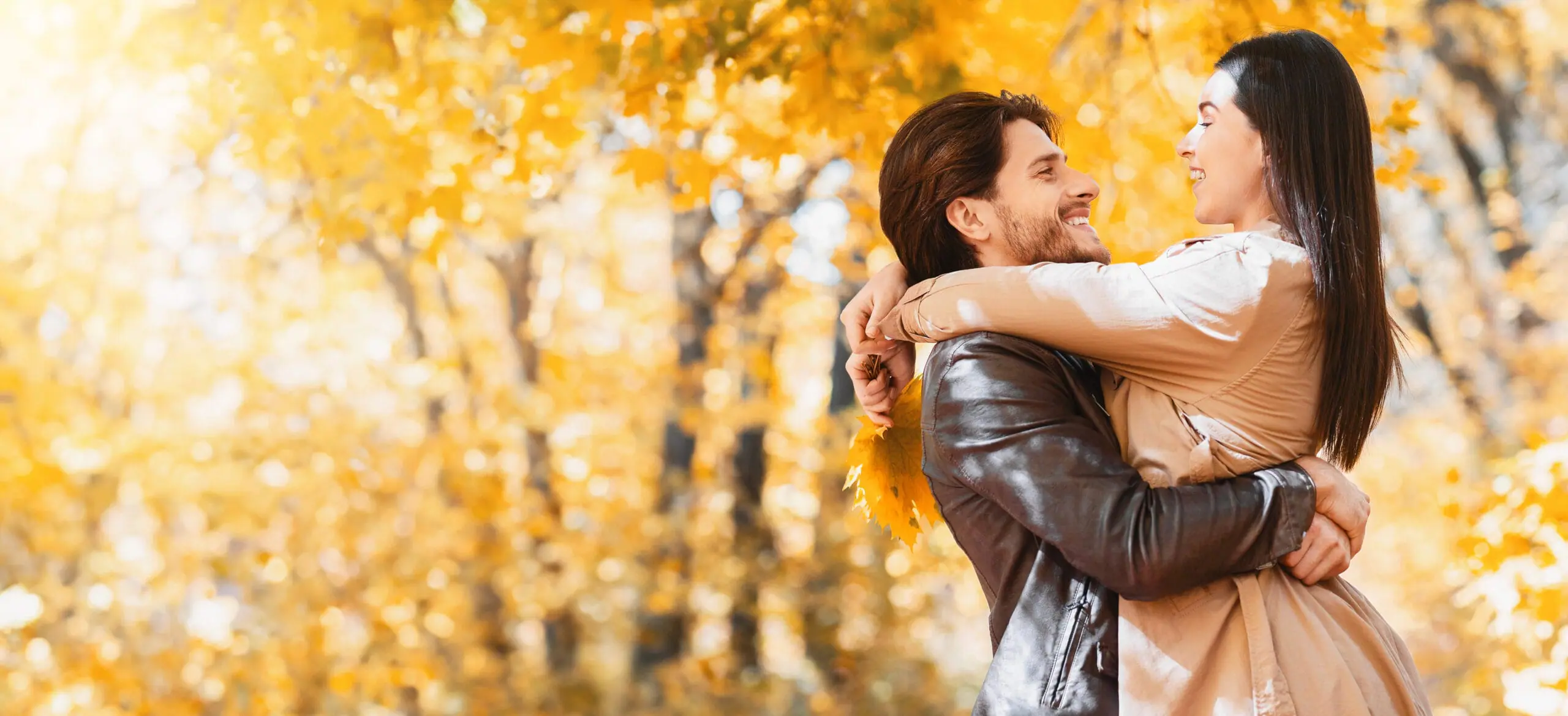 Engaged couple laughing together in a golden autumn forest during wedding planning