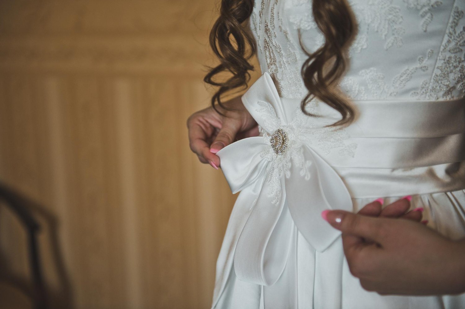 Wedding Dress Alterations: Hidden Costs and Fees the Quote May Not Show 18 The bride corrects a white bow