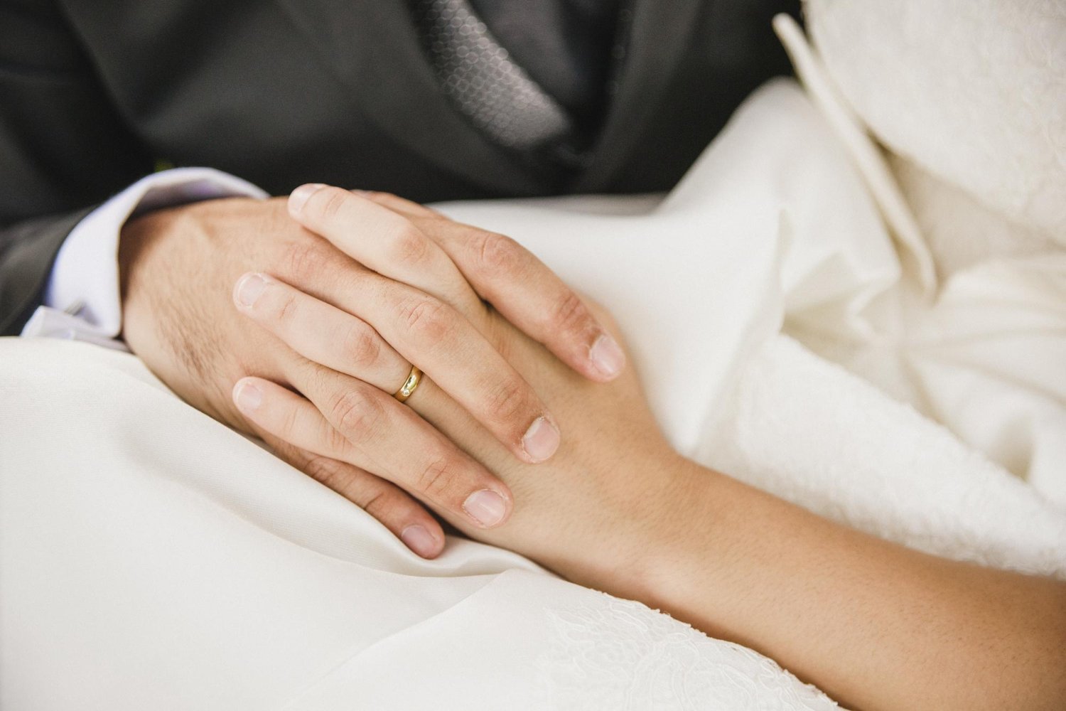 Engagement Ring Insurance: Hidden Costs and Fees the Quote May Not Show 15 Close-up of a couple holding hands during their wedding ceremony, rings visible on both hands