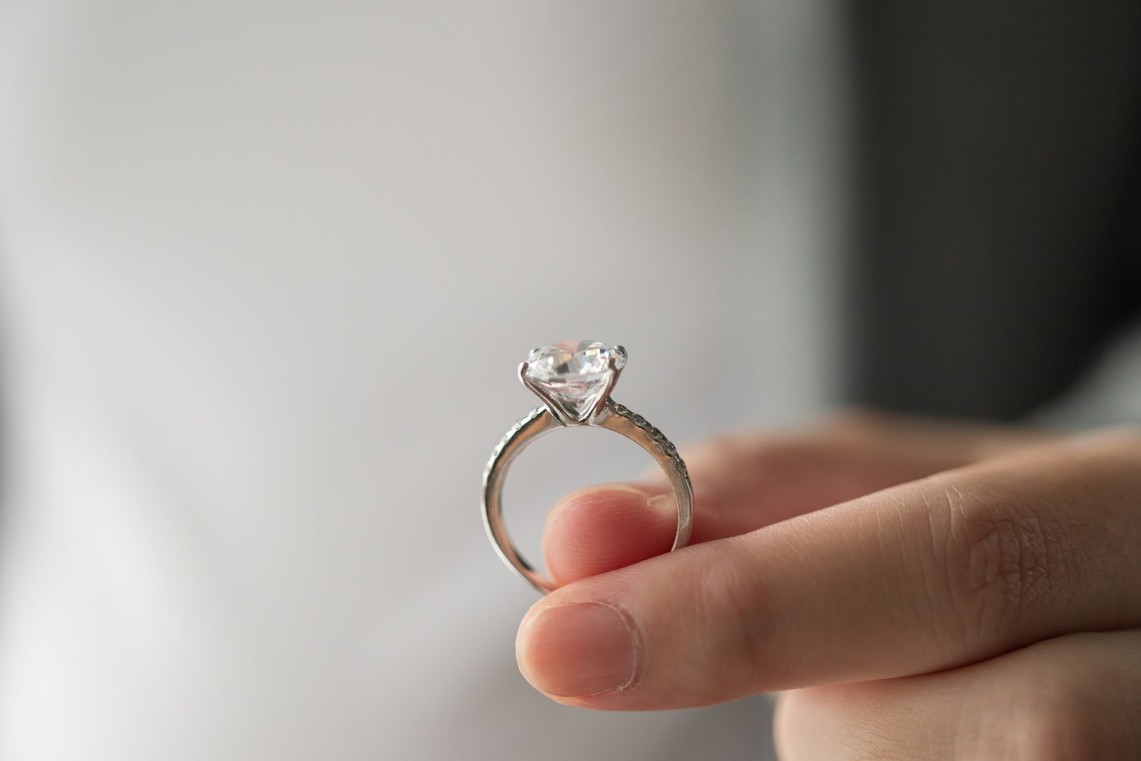 Engagement Ring Insurance: Hidden Costs and Fees the Quote May Not Show 12 Hand holding an elegant diamond ring, illustrating the jewelry insurance decision couples face after getting engaged