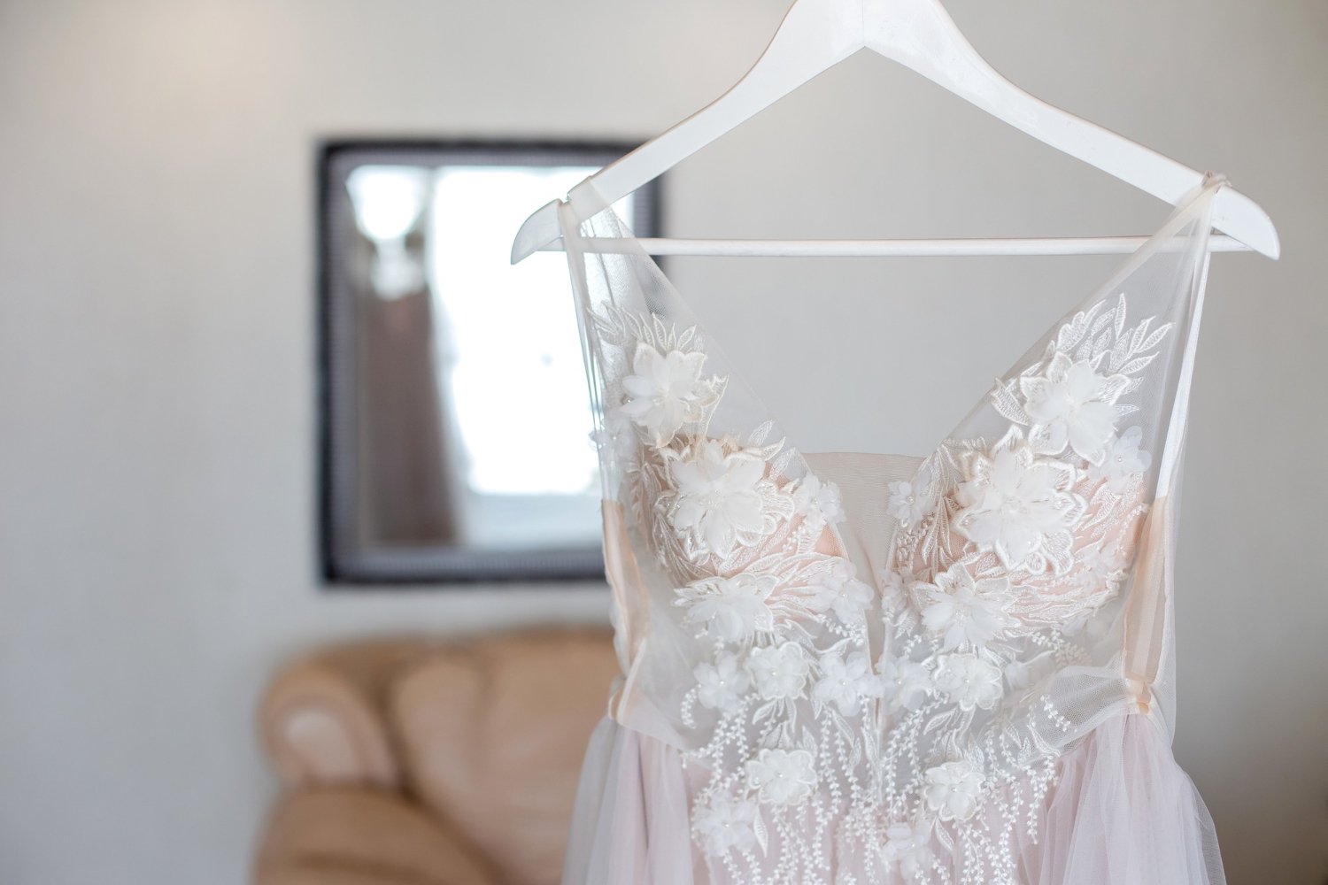 Luxury lace wedding dress hanging in soft natural light