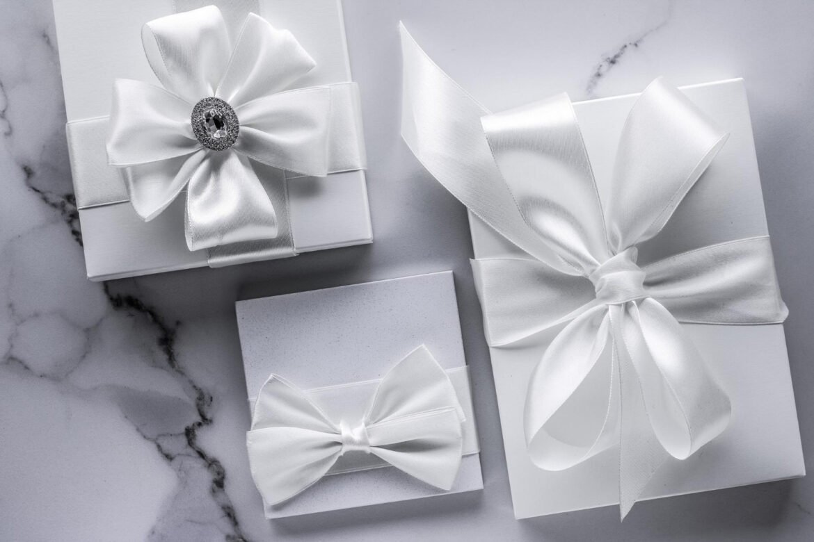Luxury wedding registry gifts wrapped in white silk bows on an elegant marble background