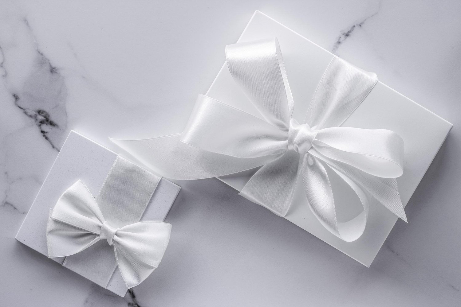 Wedding Registry Hidden Fees: What Nobody Mentions Until It Happens 11 Two elegant wedding gifts with white silk bows on marble, representing registry presents