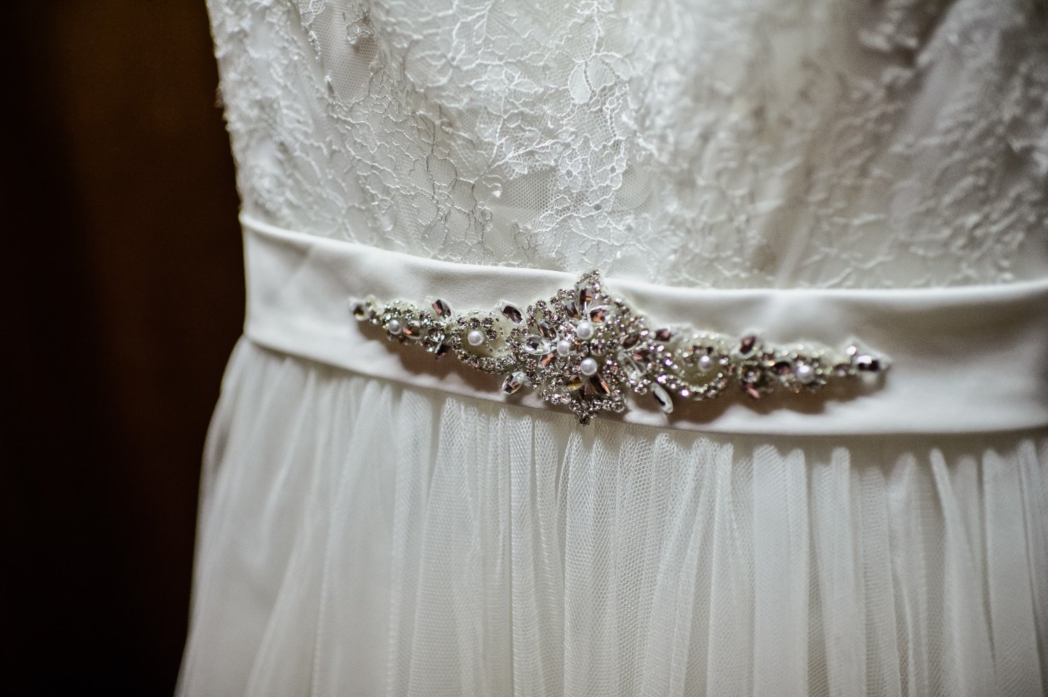 Close-up of a wedding dress crystal belt detail on delicate lace fabric