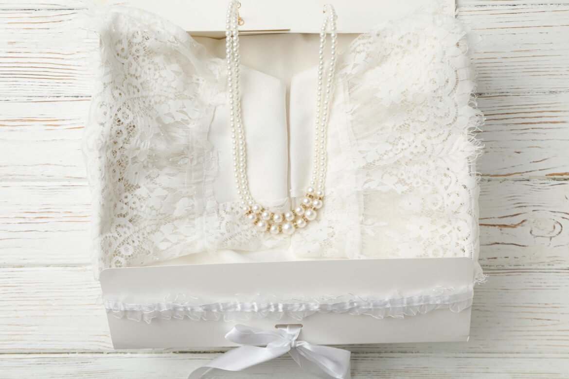 Wedding dress carefully placed in a white preservation box with a pearl necklace and lace detailing