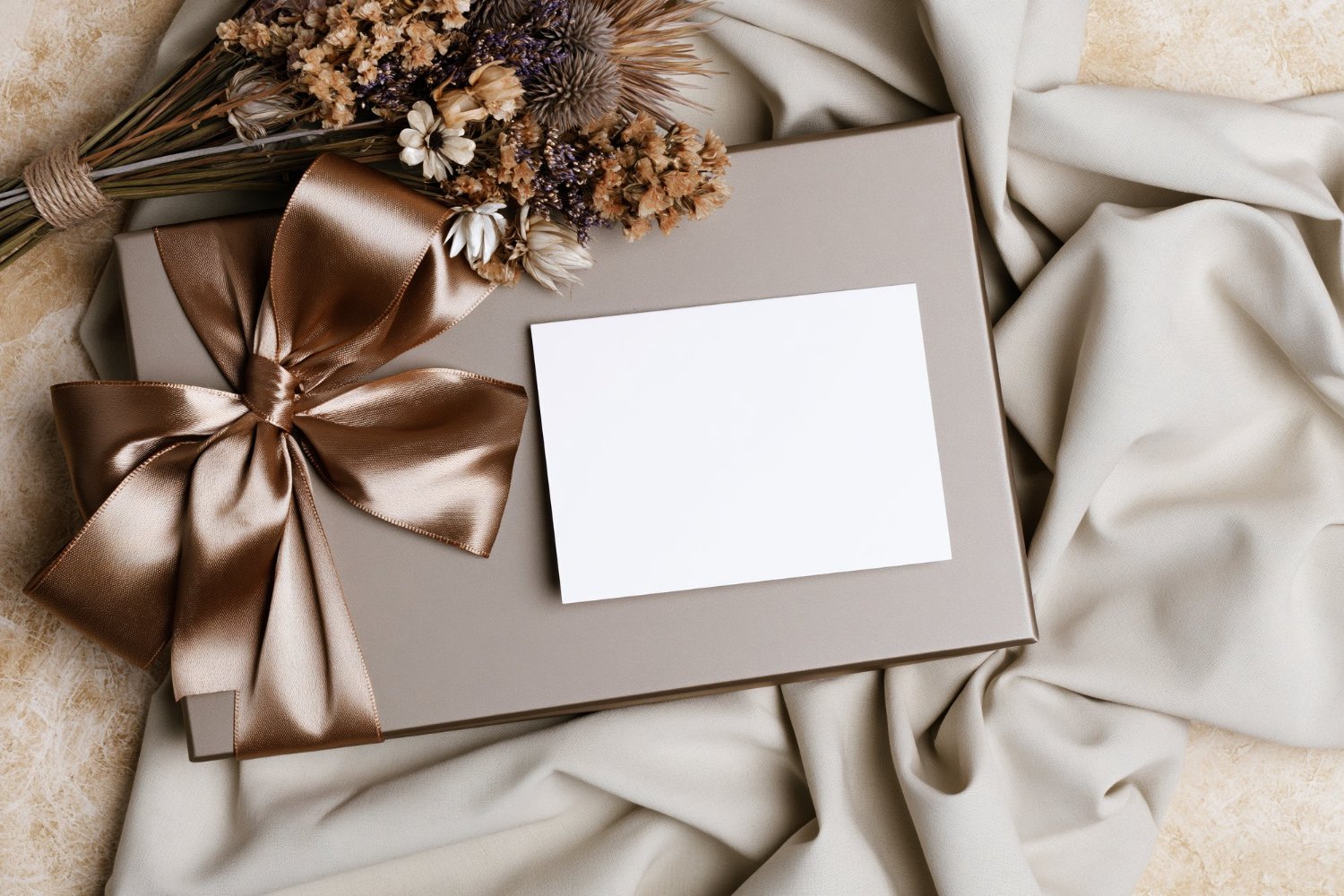 Destination Wedding Guest Costs: What to Really Expect (and How to Budget) 7 Elegant wedding gift box with satin ribbon bow and dried flowers on silk fabric