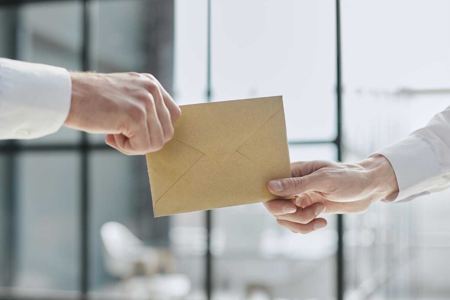 Wedding Vendor Tipping: Who to Tip, How Much, and When 10 Close-up of hands exchanging a kraft envelope for a wedding vendor tip