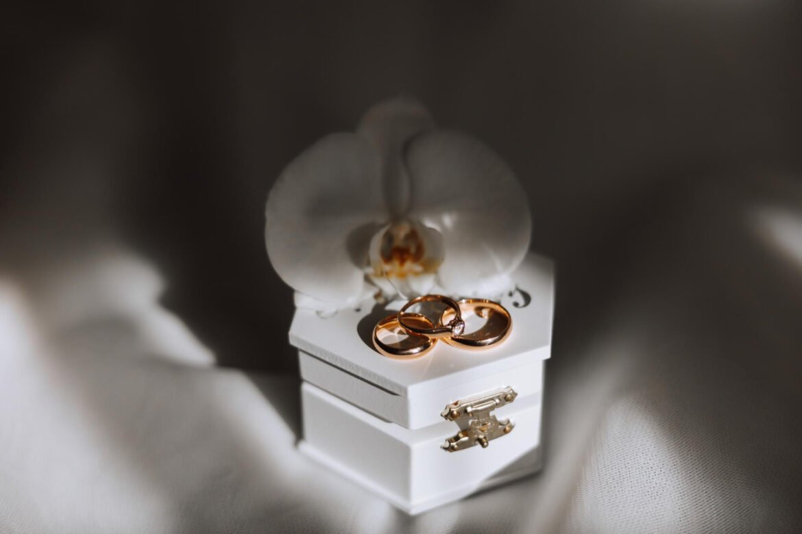 Elegant gold wedding rings resting on a white ring box with an orchid flower