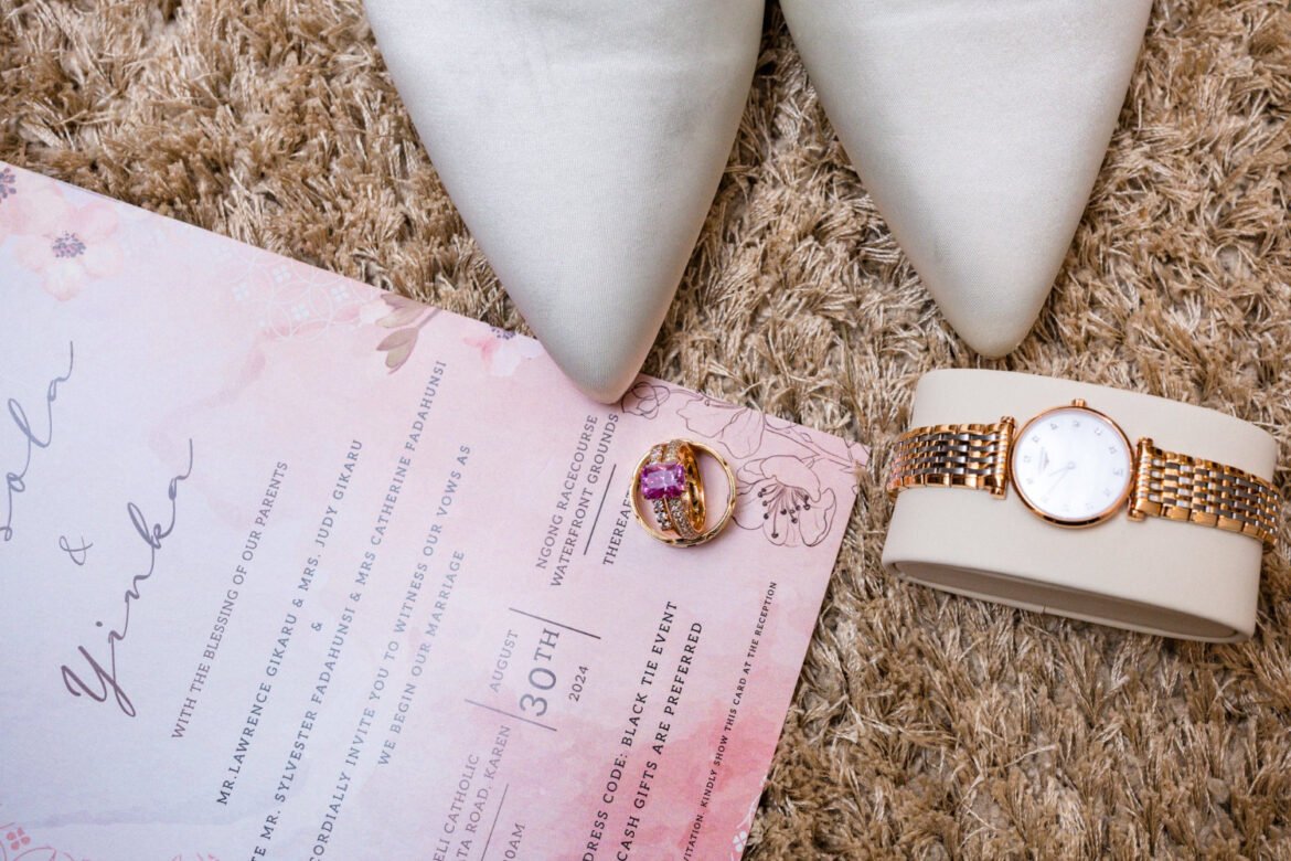 Elegant wedding invitation flatlay with gold rings, bridal shoes, and watch